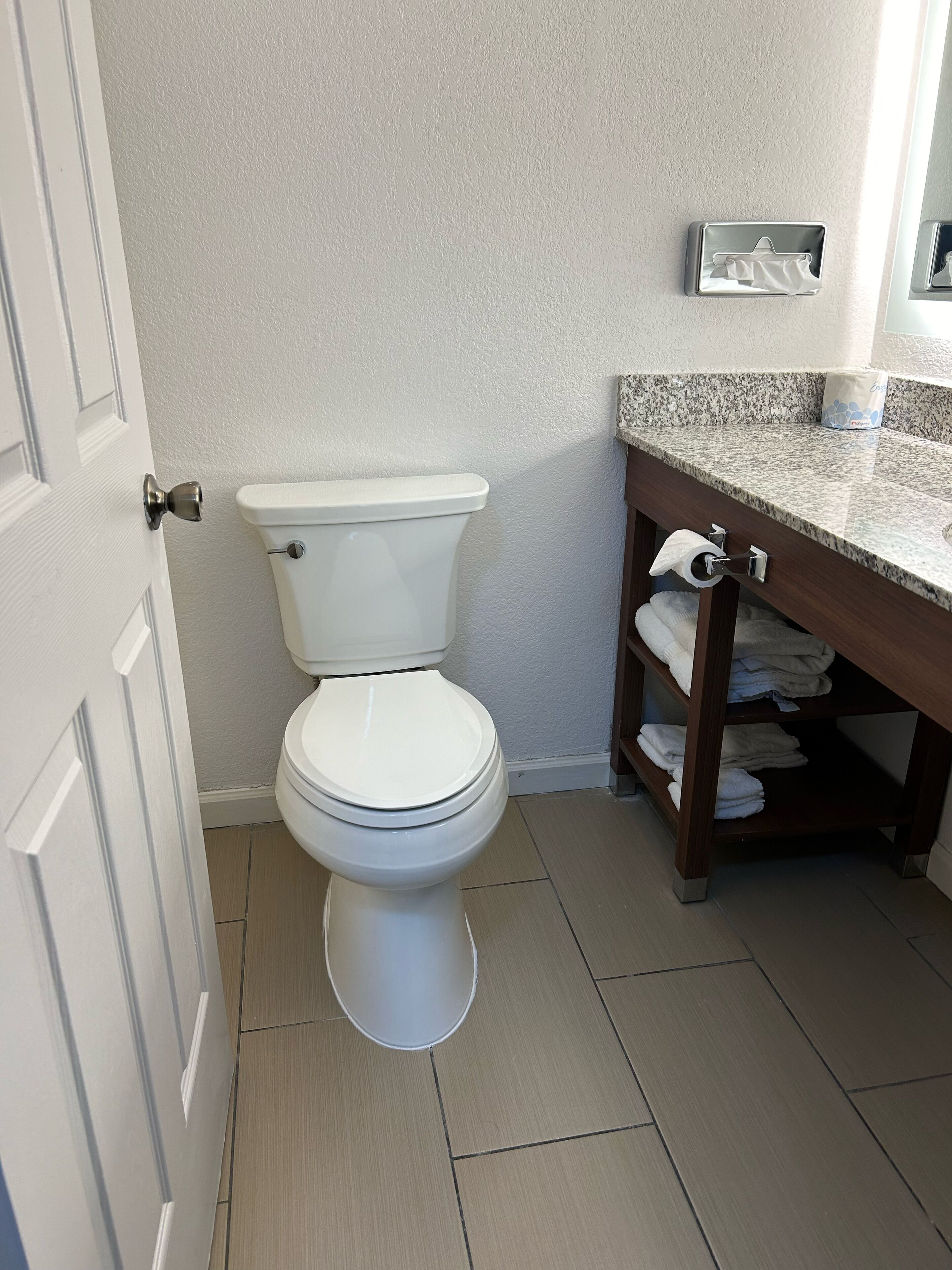 Une salle de bain comprenant des toilettes, un lavabo avec un porte-serviettes et un support à rouleau de papier toilette.