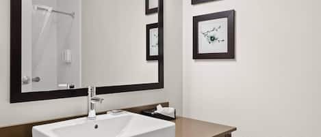A bathroom with a white sink, a large mirror, and framed artwork on the wall.