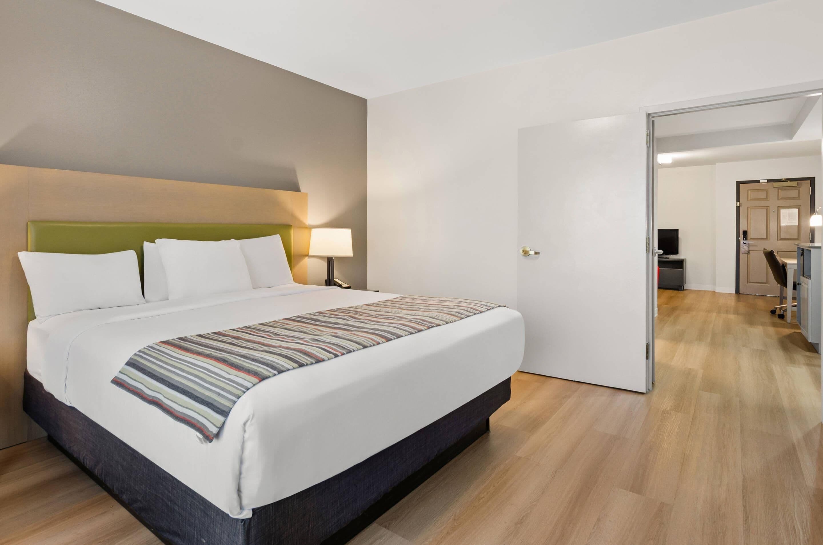 Een moderne hotelkamer met een groot bed, een groen hoofdeinde, een bedlamp en een gestreept plaid.