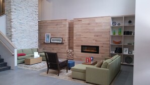 A living room with a fireplace, a sofa, a chair, and a bookshelf. - Country Inn & Suites by Radisson, Roanoke, VA (Roanoke)
