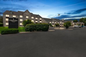 A Country Inn & Suites hotel with a modern design, featuring a large signboard, well-maintained landscaping, and a parking area.