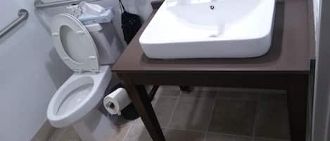 Un baño con inodoro blanco, lavamanos y un cubo de basura.