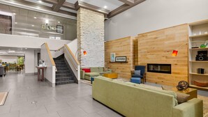 A spacious living area with a staircase, a fireplace, and a wooden wall. - Country Inn & Suites by Radisson, Roanoke, VA (Roanoke)