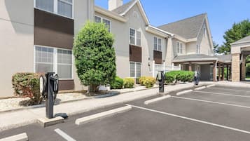 A hotel with a parking lot, electric vehicle charging stations, and a covered entrance.