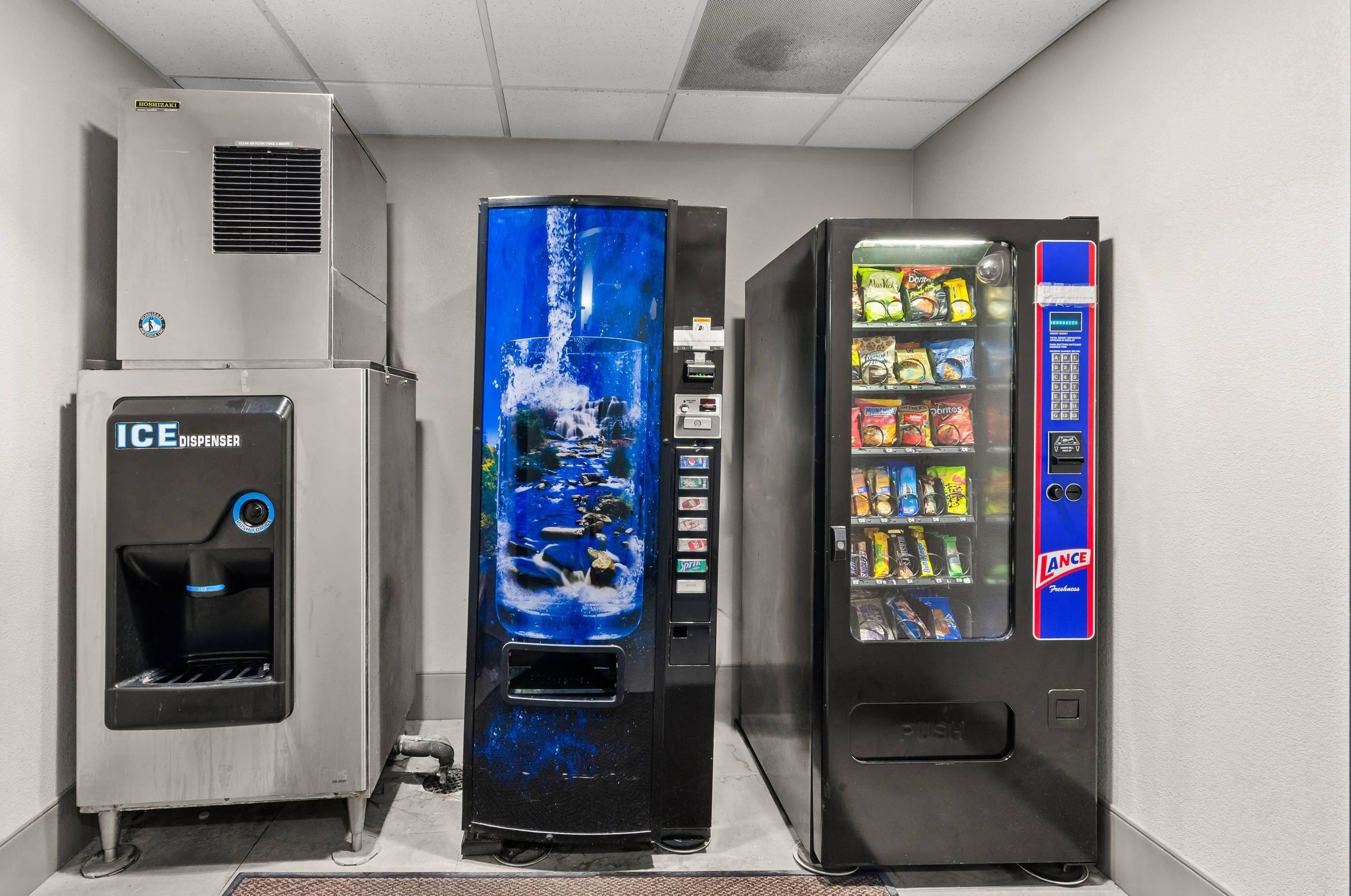 Un distributeur automatique à l’extérieur bleu et noir, un distributeur d’eau doté d’un bouton bleu, et un autre distributeur automatique de collations à l’extérieur bleu et rouge.