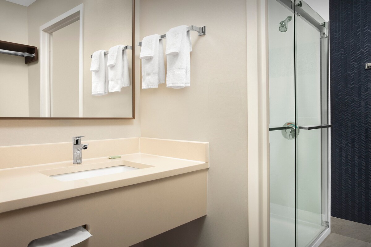 A bathroom with a sink, mirror, and hanging towels.