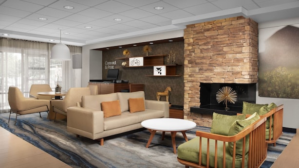 A modern living room with a sofa, armchairs, a coffee table, a fireplace, and a television. - Fairfield Inn & Suites by Marriott at Dulles Airport (Sterling)