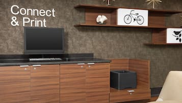 A modern kitchen with wooden cabinets, a built-in dishwasher, and a flat-screen TV. There are decorative wall shelves with a bicycle and bird illustrations.