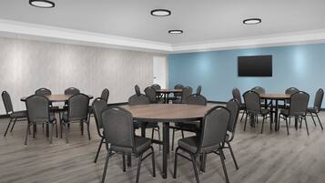 A conference room with a round table, six chairs, and a flat-screen TV on the wall.