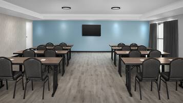 A conference room with a blue wall, a flat-screen TV, and a wooden floor.
