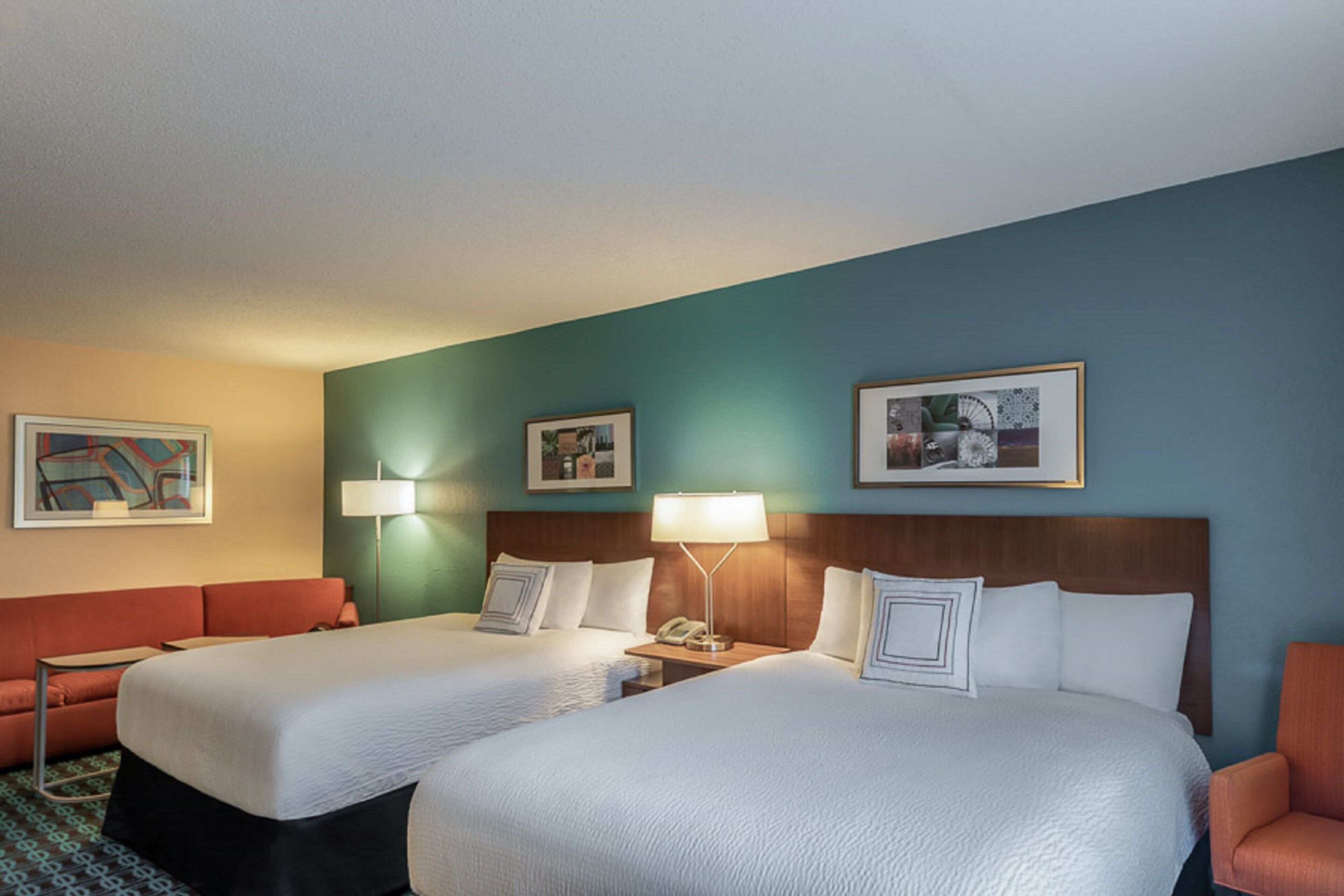 A hotel room with two beds, a sofa, and a small table.
