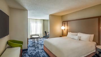 Una habitación de hotel con una cama grande, un escritorio, una silla y un televisor.