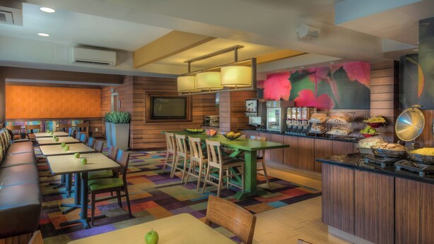 A restaurant with a long counter, multiple tables, and a buffet area with various food items.