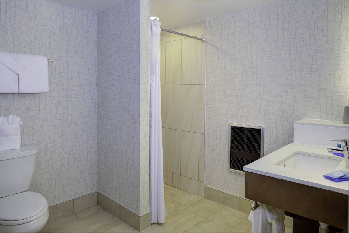 A bathroom with a toilet, shower, and sink.