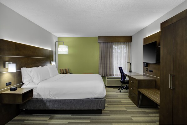 Hotelkamer met een groot bed, een bureau met stoel, een flatscreen televisie, een bureaulamp en een kledingkast.
