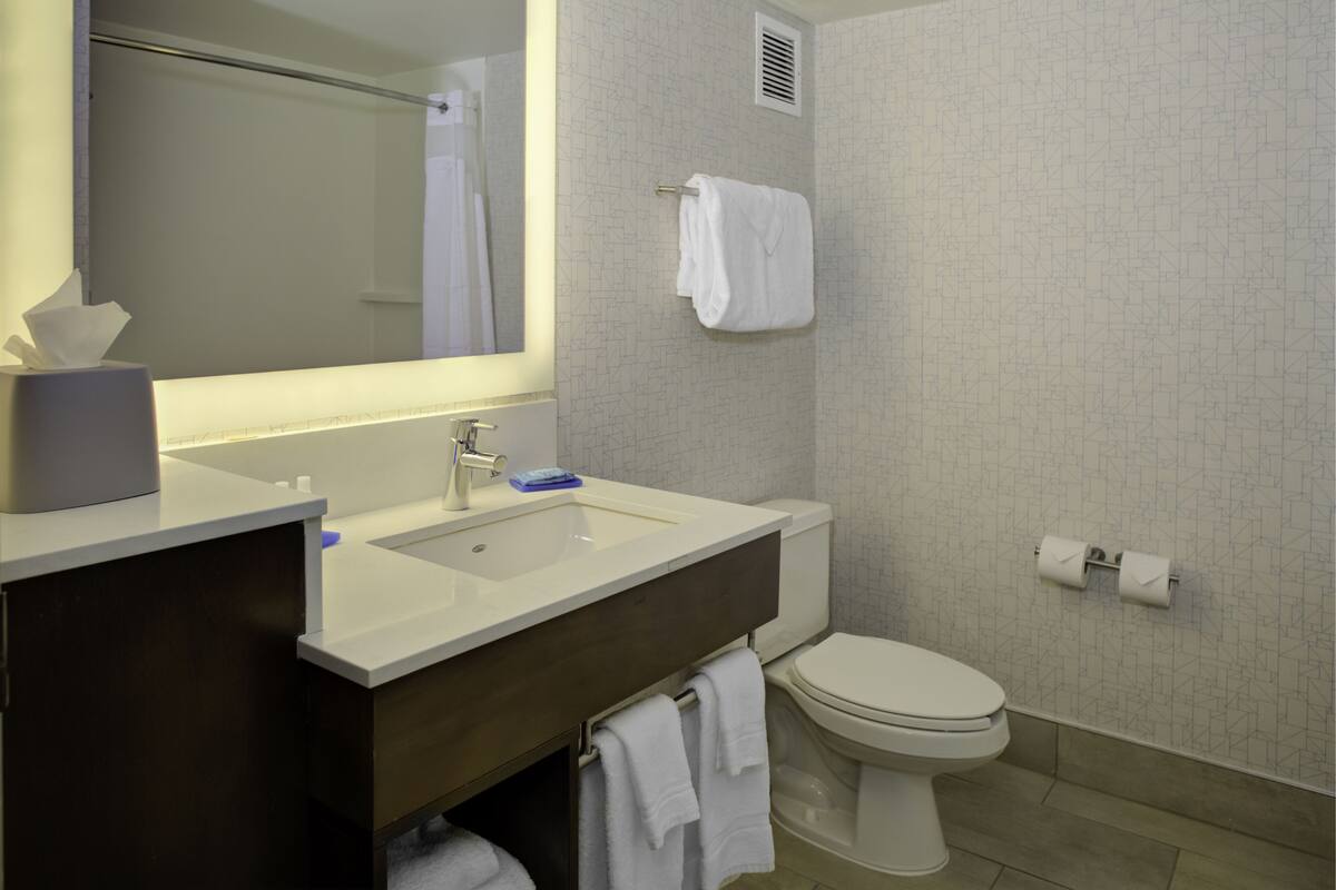 A modern bathroom with a white sink, mirror, and toilet.