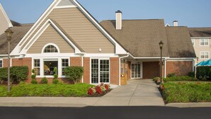 A two-story residential building with a brick facade, a pitched roof, and a front entrance with a small porch.