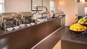 A buffet setup with multiple food stations, including a grill and a fruit display.