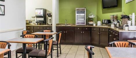 Un restaurant doté d’un mur végétal, d’une machine à café, d’un réfrigérateur et d’un téléviseur.