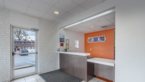 Een receptie met een wit aanmeldingsbureau, een grijs tapijt en uitzicht op de straat.
