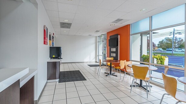 Een modern interieur met een receptiebalie, zithoek en grote ramen met uitzicht op de straat.