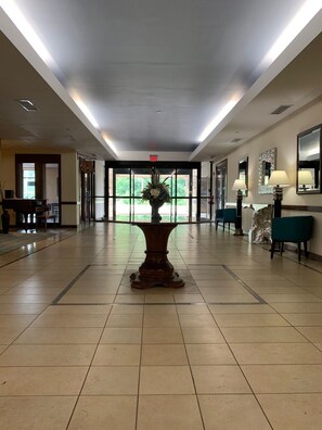 A spacious lobby with a central decorative table, a piano, and seating areas. - George Washington Hotel Busch Gardens (Williamsburg)