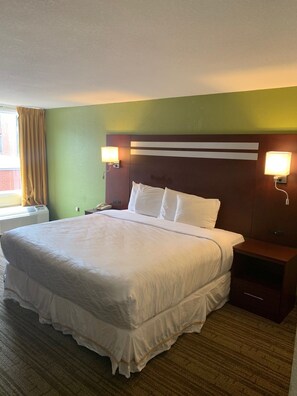 A hotel room with a large bed, two bedside tables, a headboard with horizontal stripes, and two wall-mounted lamps. - George Washington Hotel Busch Gardens (Williamsburg)