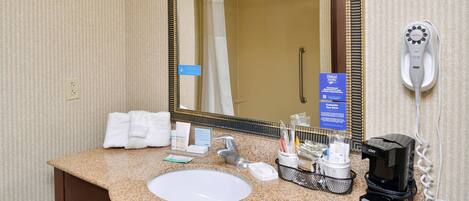 A hotel bathroom with a sink, mirror, towel rack, and a hairdryer.