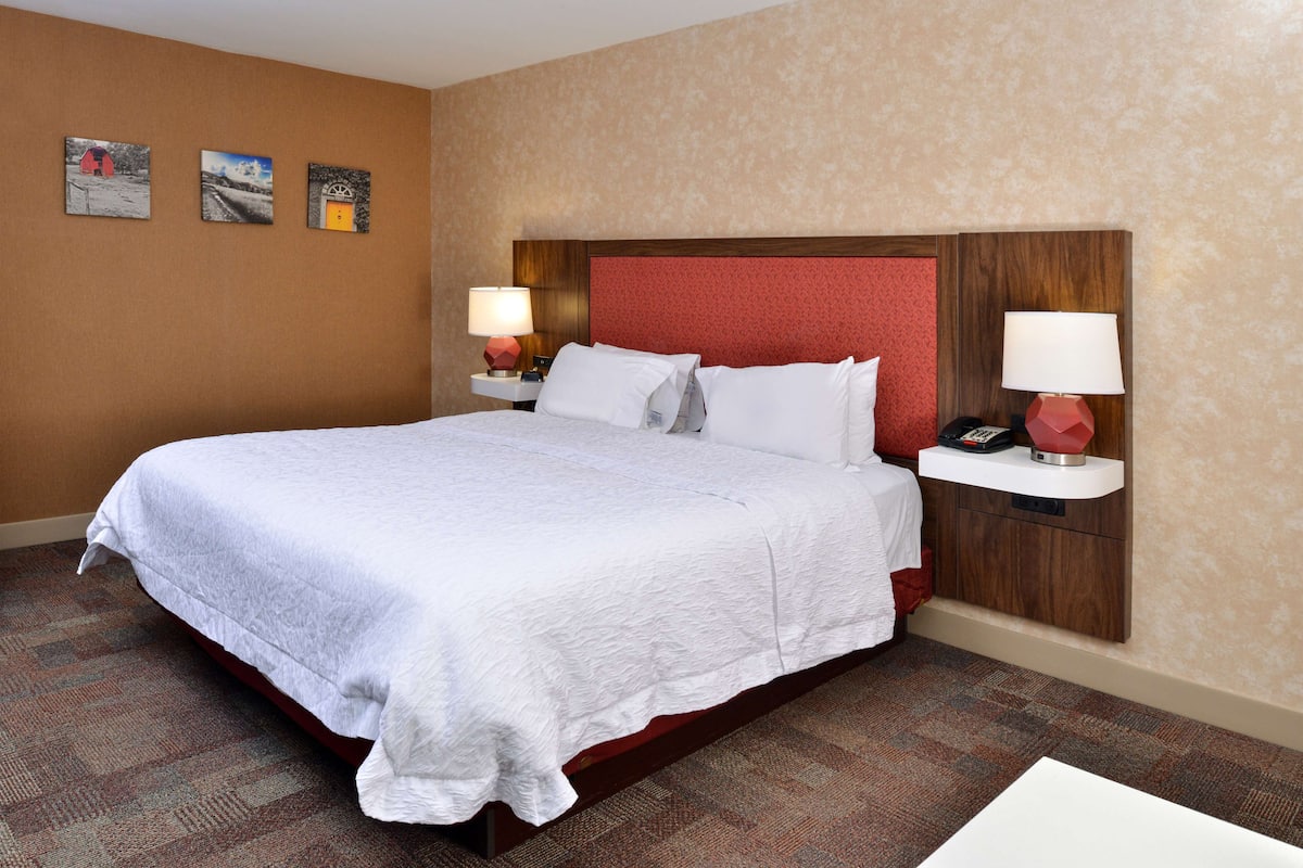 A hotel room with a large bed, two bedside tables with lamps, and three framed pictures on the wall.