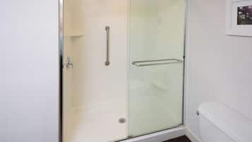 Un baño moderno con cabina de ducha de vidrio, un inodoro blanco y un cuadro en la pared.