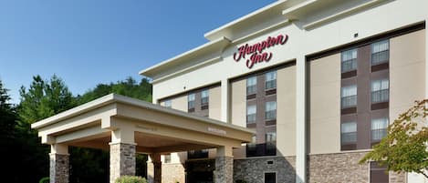 A Hampton Inn hotel with a covered entrance, stone pillars, and a clear sky.