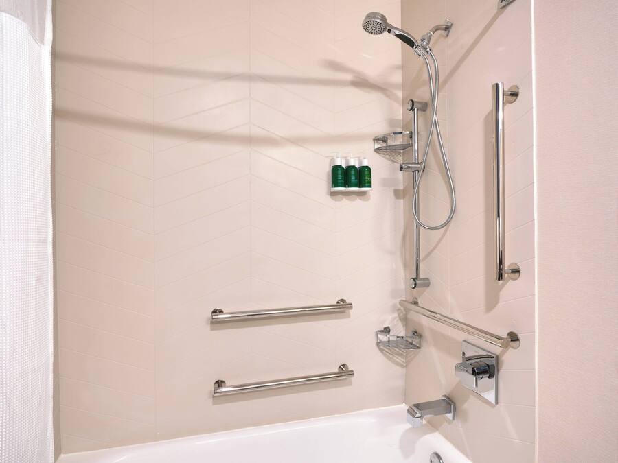 Une salle de bain équipée d’une baignoire, d’une douche et de barres d’appui.