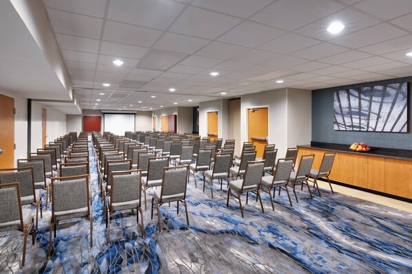 A conference room with rows of chairs, a projector screen, and a podium.