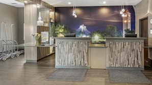A reception area with a modern design, featuring a reception desk, a clock, and a wall mural of a tower.