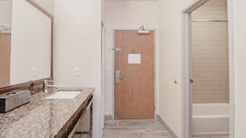 A bathroom with a wooden door, a sink, and a mirror.
