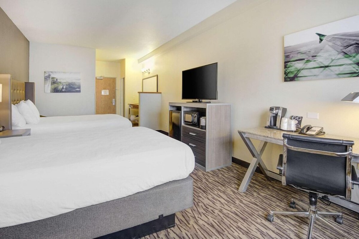 Une chambre d’hôtel avec un grand lit, un bureau avec une chaise, une télévision et une machine à café.