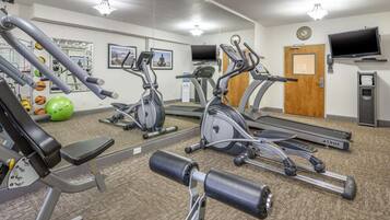 A gym with various exercise equipment including treadmills, elliptical machines, and weight machines.