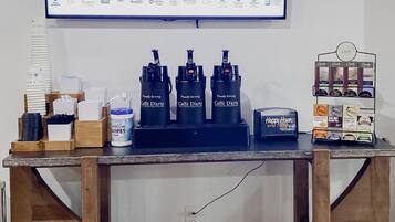 Un mostrador de recepción de hotel con un televisor mostrando información del hotel, una estación de café y una estación de té.