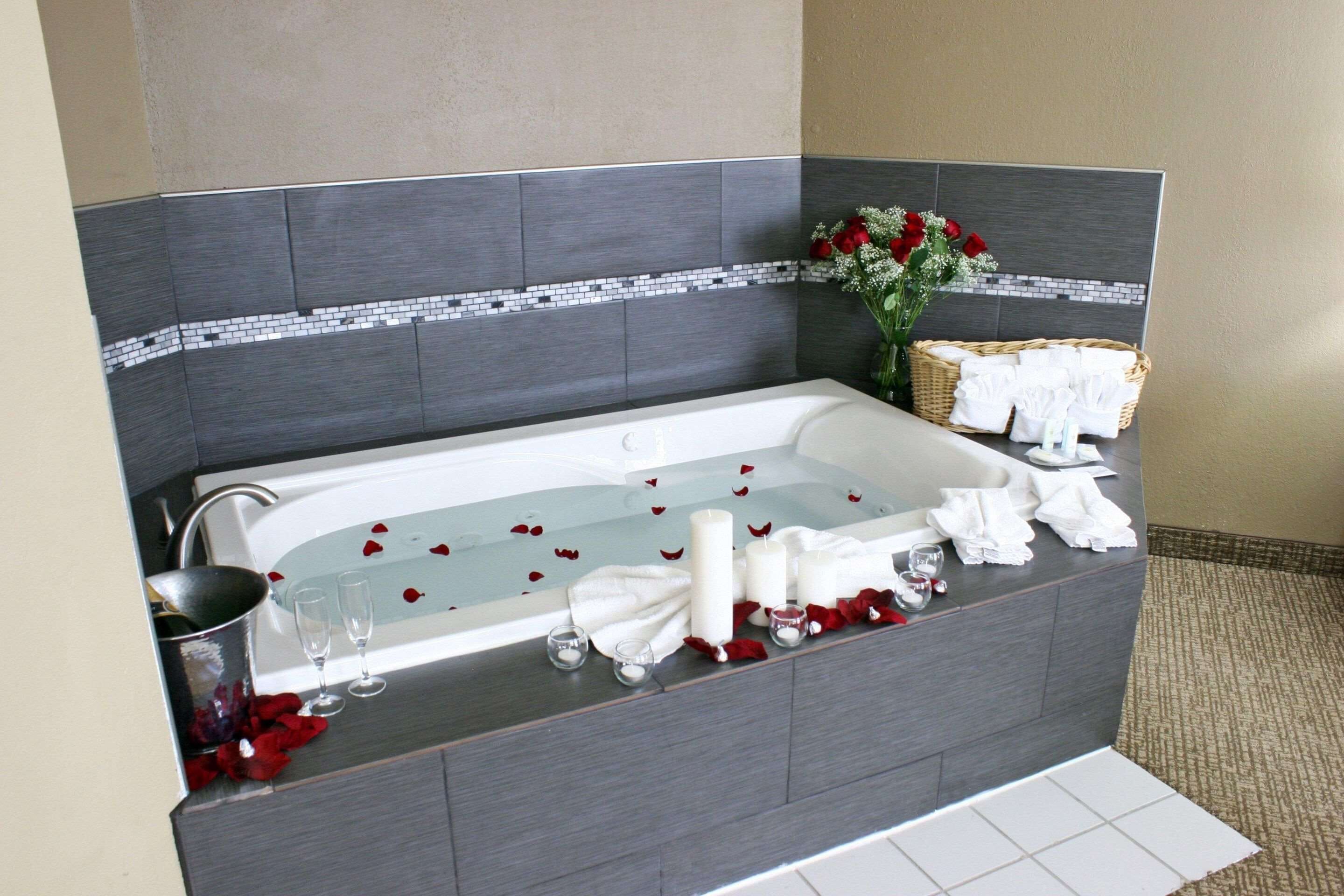 Un baño moderno con una bañera grande, un lavamanos y un florero decorativo con flores.