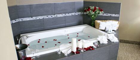 Un baño moderno con una bañera grande, un lavamanos y un florero decorativo con flores.