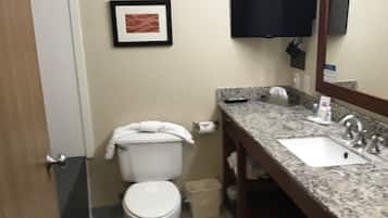 A bathroom with a toilet, sink, and a television mounted on the wall.