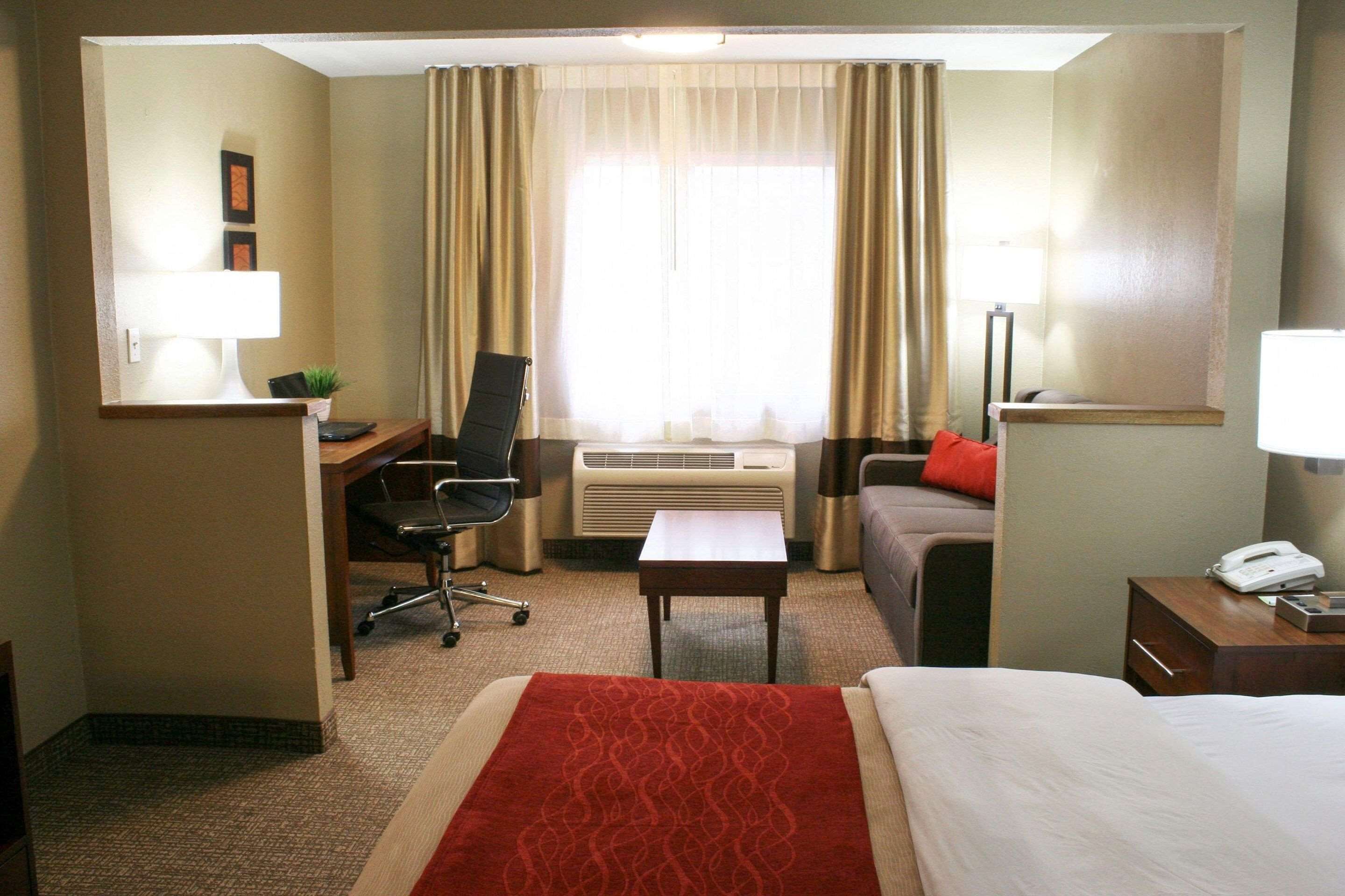 Una habitación de hotel con cama, escritorio, silla y una mesita.