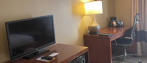 Une chambre d’hôtel équipée d’une télévision, d’un bureau, d’une lampe, d’un four à micro-ondes et d’un réfrigérateur.