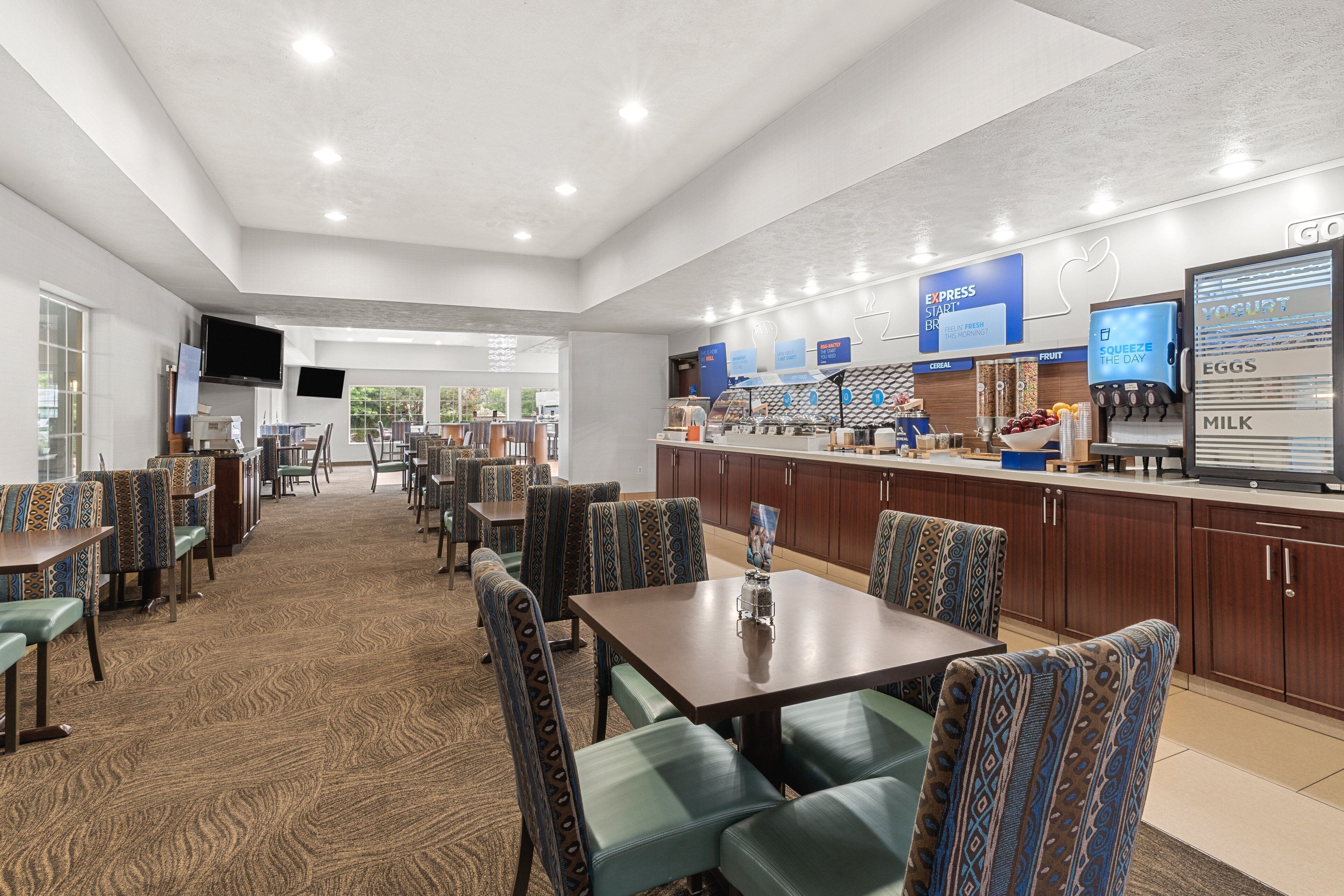 A modern breakfast area with seating, a counter with food and drink options, and a television.
