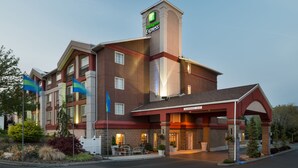 A Holiday Inn Express hotel with a brick facade, multiple balconies, and a covered entrance. - Holiday Inn Express Wenatchee by IHG (Wenatchee)