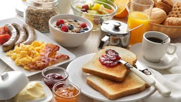 Une table de petit-déjeuner avec divers aliments, notamment des toasts, de la confiture, du beurre et une tasse de café.