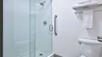 A modern bathroom with a glass-enclosed shower, a white toilet, and a towel rack with folded towels.