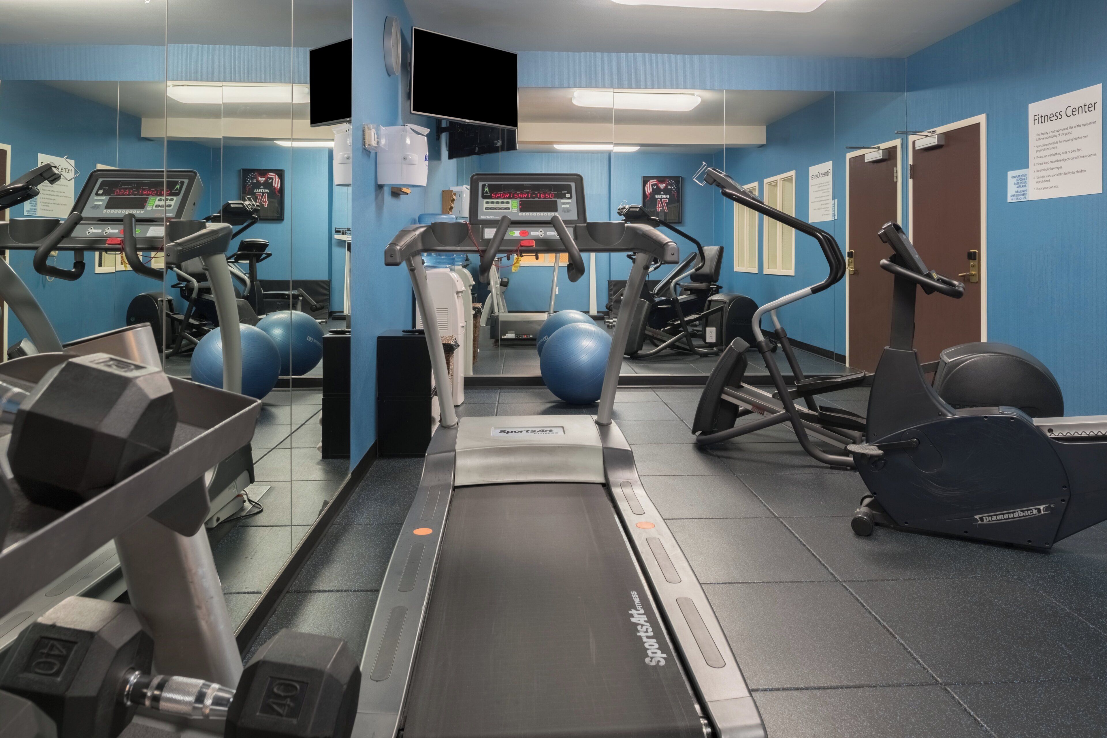 Un gimnasio con equipo de cardio, máquinas de pesas y pelotas de ejercicio.