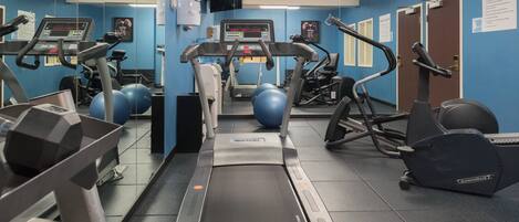 Un gimnasio con equipo de cardio, máquinas de pesas y pelotas de ejercicio.