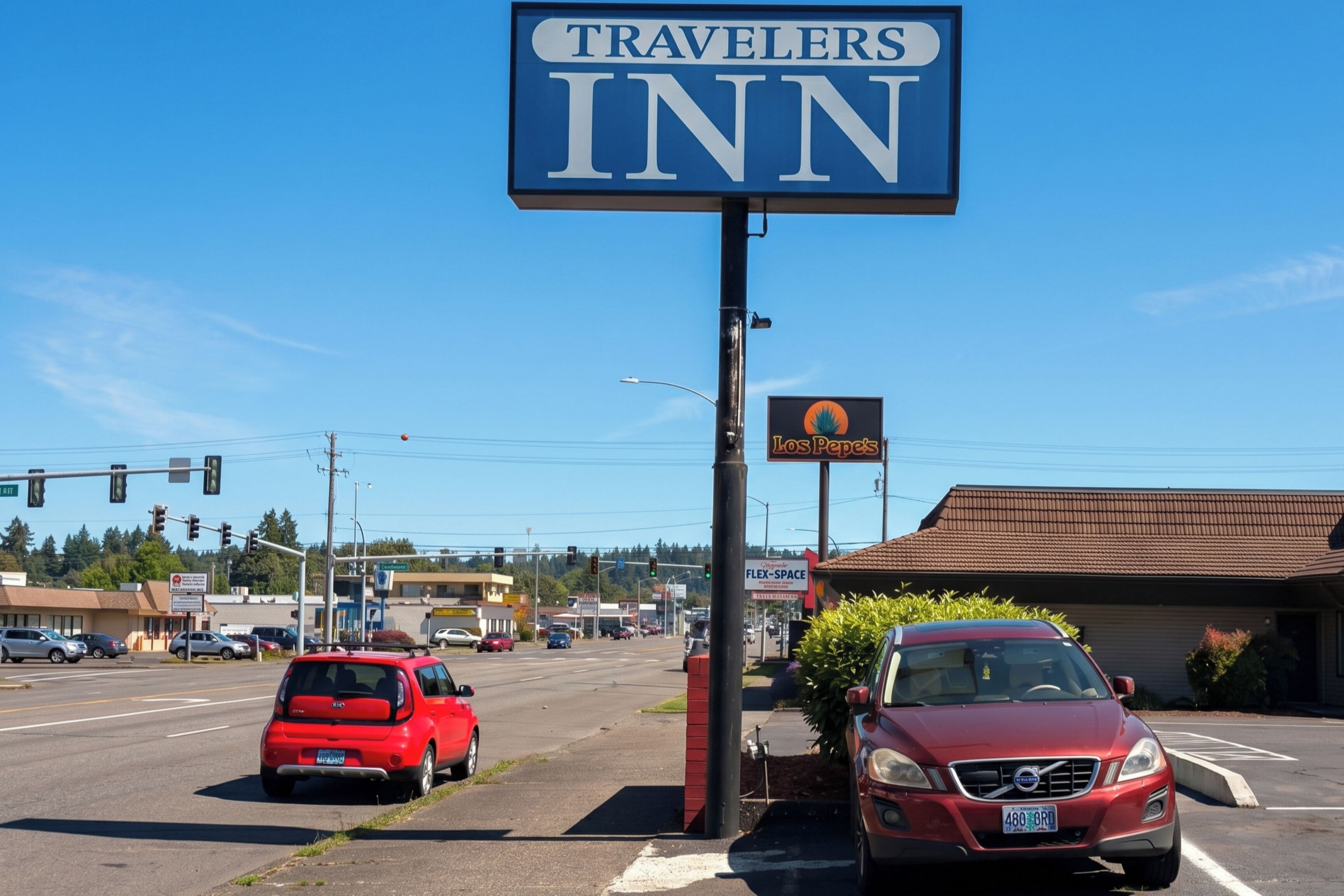 Señal de Travelers Inn, un estacionamiento y un edificio con techo rojo.